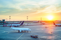 Airplanes on a runway at an airport during sunset.