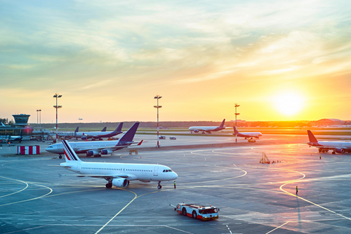 Airplanes on a runway at an airport during sunset.